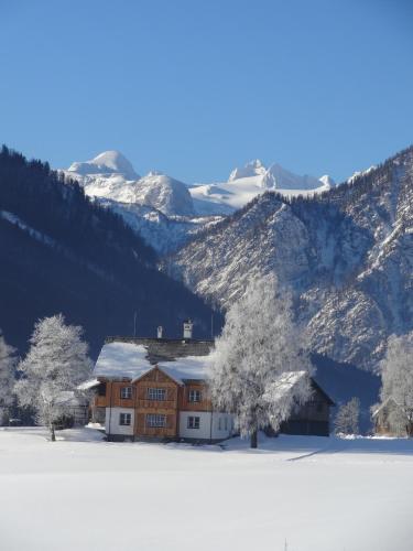 a house in the snow in front of a mountain at Stangl - Hof in Bad Aussee