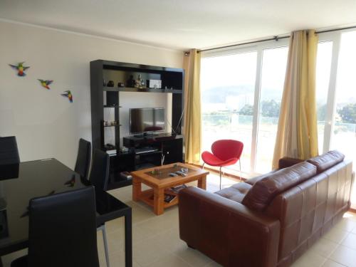 a living room with a couch and a table and a television at Papudo Laguna in Papudo
