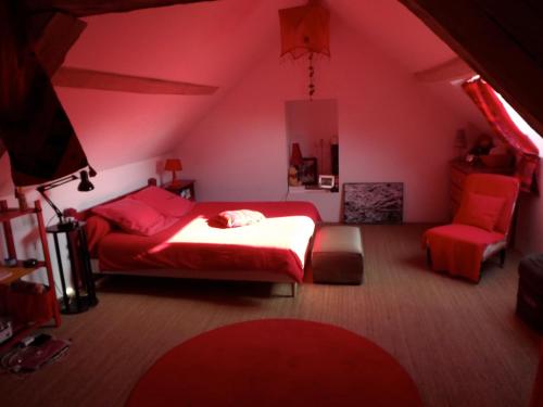 1 dormitorio con 1 cama roja y 1 silla en Les Anniquins, en Ivoy-le-Pré