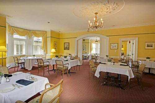 Briars Resort and Spa في Georgina: غرفة طعام مع طاولات وكراسي وثريا