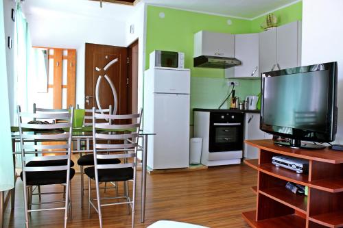 ein Wohnzimmer mit einer Küche mit einem TV und Stühlen in der Unterkunft Apartments Tragurion in Trogir