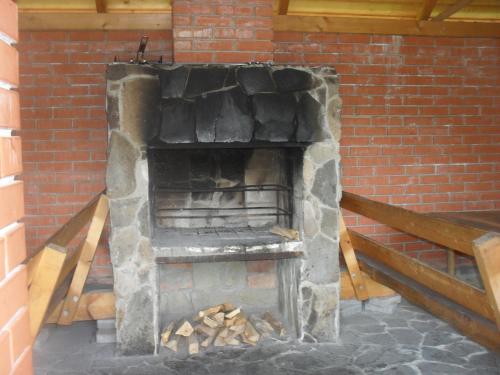 a stone fireplace in a brick building with wood inside at Cottage Zhelikhovskykh in Tatariv