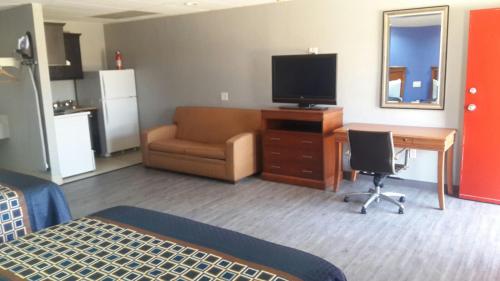 a living room with a television and a desk with a chair at Paris Inn and Suites in Paris