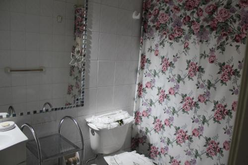 y baño con aseo y cortina de ducha con motivos florales. en Amplia y Acogedora Casa en Puerto Montt, en Puerto Montt