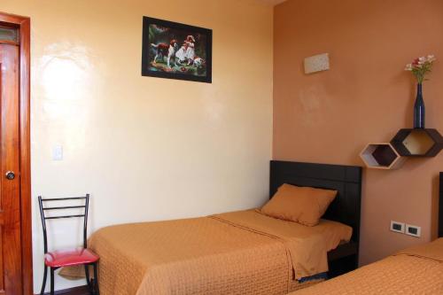 a bedroom with two beds and a pink chair at Hotel Norte in Cuenca