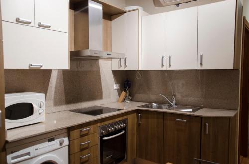 a kitchen with white cabinets and a sink and a microwave at Apartaments El Jaç in Montblanc