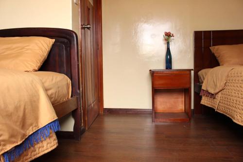a room with two beds and a vase of flowers on a table at Hotel Norte in Cuenca