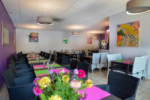 a dining room with tables and chairs and flowers at Brasserie Michel / Cesar Hotel in Le Portel