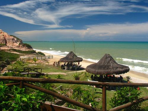 a beach with some straw umbrellas and the ocean at Quiriri Park Hotel in Prado