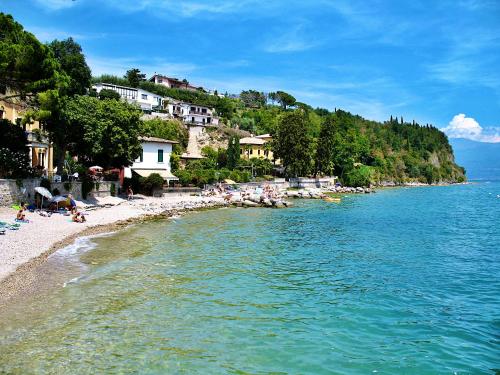 a beach with people sitting on the sand and the water at Residence Bellavista in Manerba del Garda