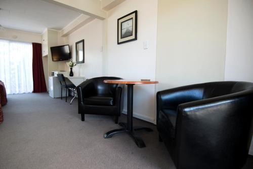 a living room with a chair and a desk at Kapiti Gateway Motel in Waikanae