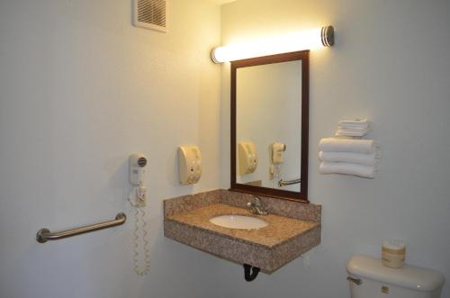 a bathroom with a sink and a mirror and a toilet at Welcome Inn Corona in Corona