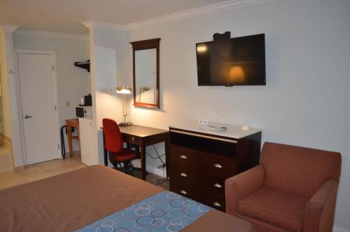 a bedroom with a bed and a desk and a chair at Welcome Inn Corona in Corona