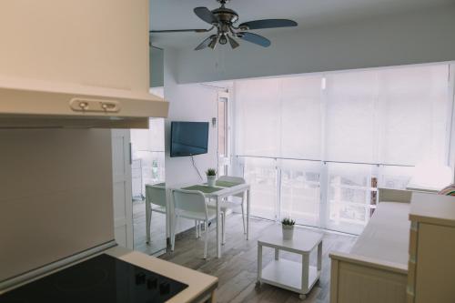 cocina con mesa y sillas y ventilador de techo en Apartamento Malagueta Playa, en Málaga