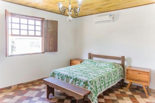 um quarto com uma cama, uma mesa e uma janela em Pouso copo de leite em Tiradentes
