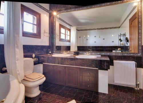 a bathroom with two sinks and a toilet and a mirror at Infinity Villa Ioannina in Ioannina