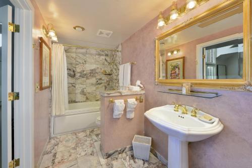 a bathroom with a sink, mirror and bathtub at Hotel La Rose in Santa Rosa