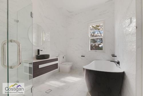 ein Bad mit einer Badewanne, einem WC und einem Fenster in der Unterkunft The Summit House in Katoomba