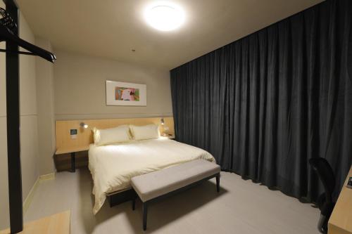 a bedroom with a bed and a bench in it at Jinjiang Inn Suzhou Railway Station North Square in Suzhou