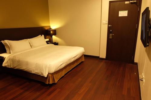 a hotel room with a bed and a door at Lazenda Hotel in Labuan