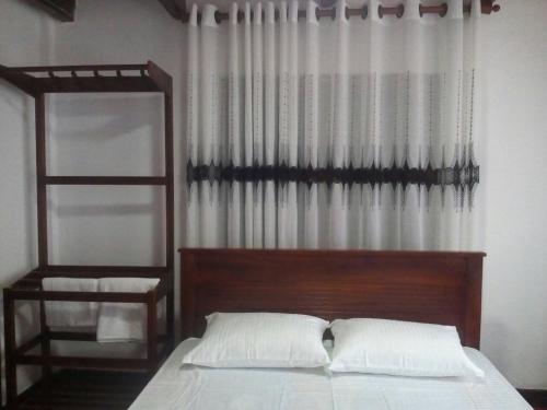 a bedroom with a bed with a wooden headboard and a window at Walawwa Guest House in Matale