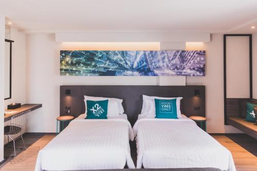 a hotel room with two beds and a tv at Cross Vibe Bangkok Sukhumvit in Bangkok