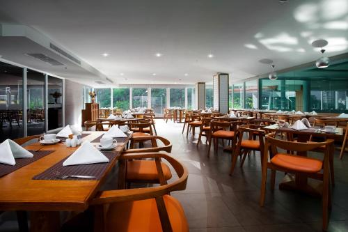 un restaurante con mesas y sillas de madera y ventanas en Balihai Bay Pattaya, en Pattaya South