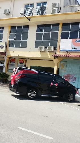 a black limo parked in front of a building at Mass Hotel in Kampong Kerayong
