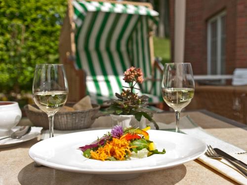 a plate of food on a table with two wine glasses at Flair Landhotel Strengliner Mühle in Pronstorf
