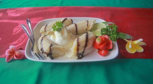 a plate of food with cake and strawberries on a table at Balangan Sea View Bungalow in Jimbaran