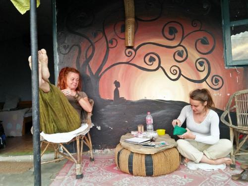 two women sitting in chairs in front of a wall at Peace Guest House in Pokhara