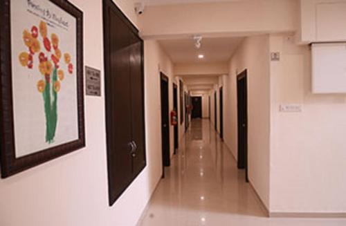 a hallway in a hospital with a painting of flowers on the wall at Malhar Grand in Jejūri