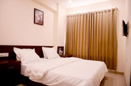a bedroom with a large white bed and a window at Malhar Grand in Jejūri