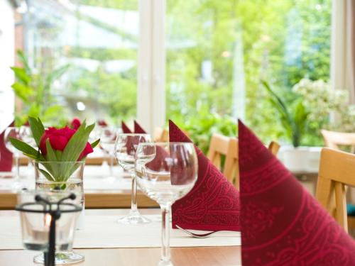 a table with wine glasses and a vase of flowers at Flair Landhotel Strengliner Mühle in Pronstorf