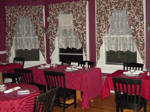 a dining room with red tables and chairs and windows at Brookview Manor Inn in Canadensis