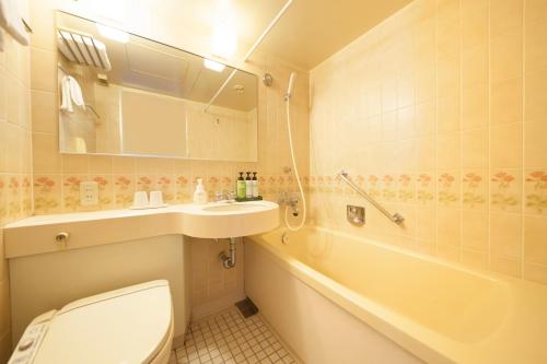 a bathroom with a toilet and a sink and a tub at Quintessa Hotel Ogaki in Ogaki
