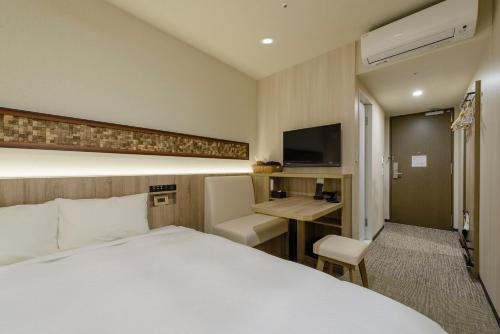東京にあるホテルイルフィオーレ葛西のベッドとデスクが備わるホテルルームです。
