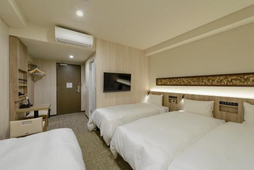 a hotel room with two beds and a television at Hotel Il Fiore Kasai in Tokyo