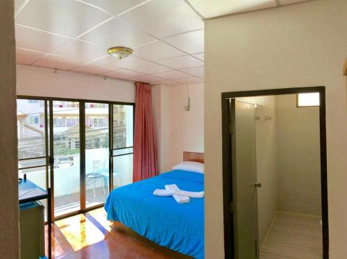 sypialnia z niebieskim łóżkiem i przesuwnymi szklanymi drzwiami w obiekcie Malee House and Restaurant w mieście Pattaya Central