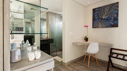 baño con ducha de cristal y silla blanca en Hotel Daun Bali Seminyak, en Seminyak