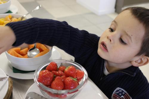 a young boy is looking at a bowl of strawberries at Hotel Bocciolo in Orta San Giulio