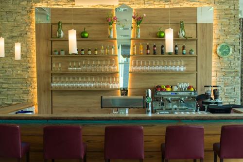 a bar at a restaurant with purple chairs at Gesundheitszentrum Bärenhof in Bad Gastein
