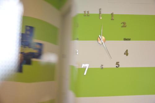 a clock on a green wall with numbers on it at Hotel Etnea Royal Suites in Catania