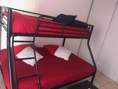 - un lit superposé avec des draps rouges et des oreillers blancs dans l'établissement Domaine de Bussy, à Bussy-Saint-Georges