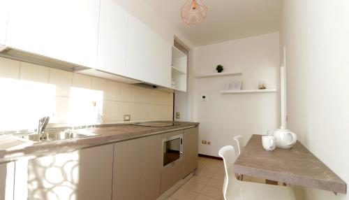 een keuken met witte kasten, een wastafel en een tafel bij Italianway-Bergognone 47 Flat in Milaan