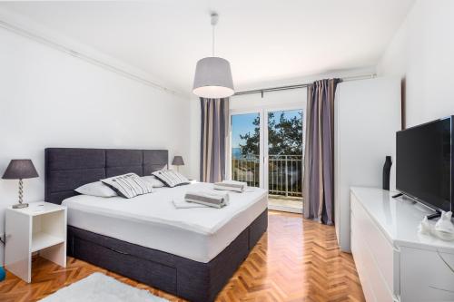 a white bedroom with a large bed and a tv at Villa Lovran, heated pool and Spa in Lovran