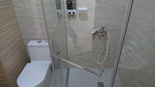 a shower with a glass door next to a toilet at Taitung Tourist Inn in Taitung City
