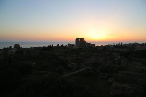 a sunset over a castle on top of a hill at Aleph Boutique Hotel in Jbeil