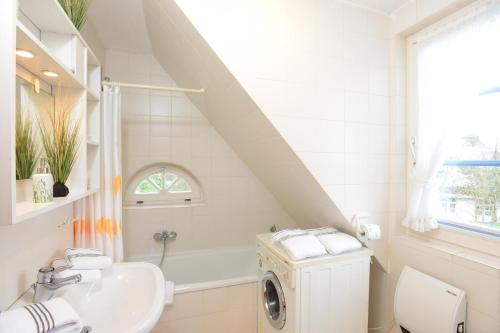 a bathroom with a sink and a washing machine at Wohnung-Wattseite in Munkmarsch