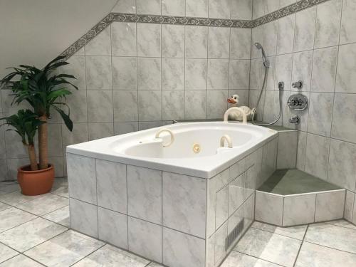 La salle de bains est pourvue d'une baignoire et d'une plante en pot. dans l'établissement Hotel Zartenbach B&B, à Hinterzarten